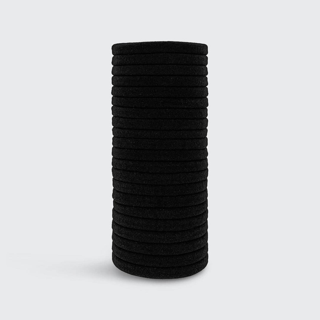 Pile d’élastiques noirs KITSCH en nylon recyclé présentée sur fond gris clair, accessoires coiffure écologiques pour tous types de cheveux