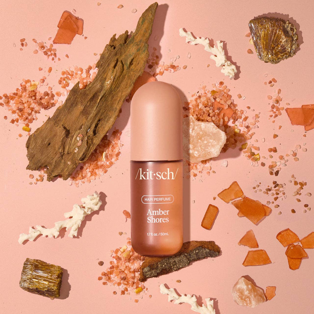 Parfum pour cheveux KITSCH Amber Shores 50 ml avec vaporisateur ouvert, flacon rose poudré mat sur fond beige minimaliste, photo produit professionnelle.