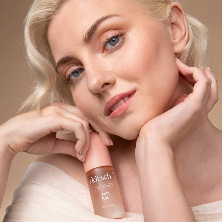 Femme aux cheveux blonds tenant le parfum pour cheveux KITSCH Tula Rose 50 ml près de son visage. Parfum capillaire floral pour rafraîchir et parfumer les cheveux.