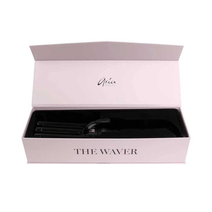 Ondulateur triple tube ARIA Beauty noir présenté dans une boîte rose pâle ouverte avec intérieur noir, outil coiffant professionnel pour créer des vagues effet plage, bohème ou rétro.
