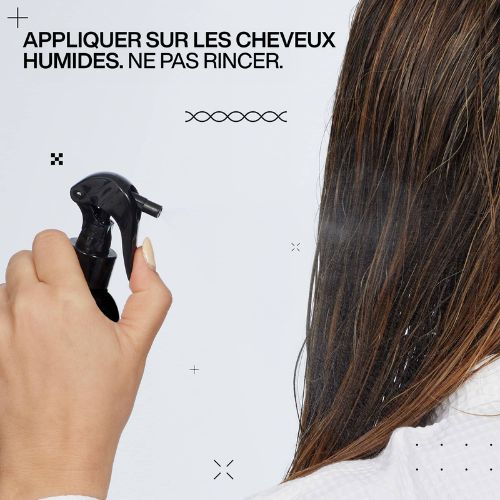 Gros plan du pulvérisateur noir REDKEN Acidic Color Gloss avec étiquette rose indiquant traitement thermo-protecteur pour cheveux colorés.