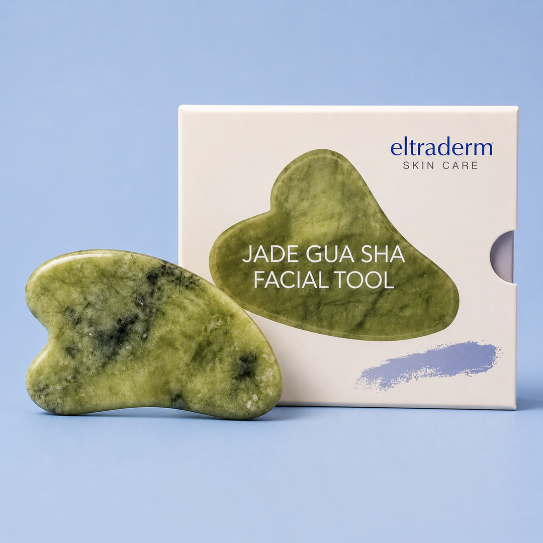 Gua Sha facial Eltraderm en jade Xiuyan vert marbré avec fini poli, présenté devant son emballage blanc sur fond bleu clair, outil de massage visage professionnel pour drainage lymphatique et éclat de la peau.