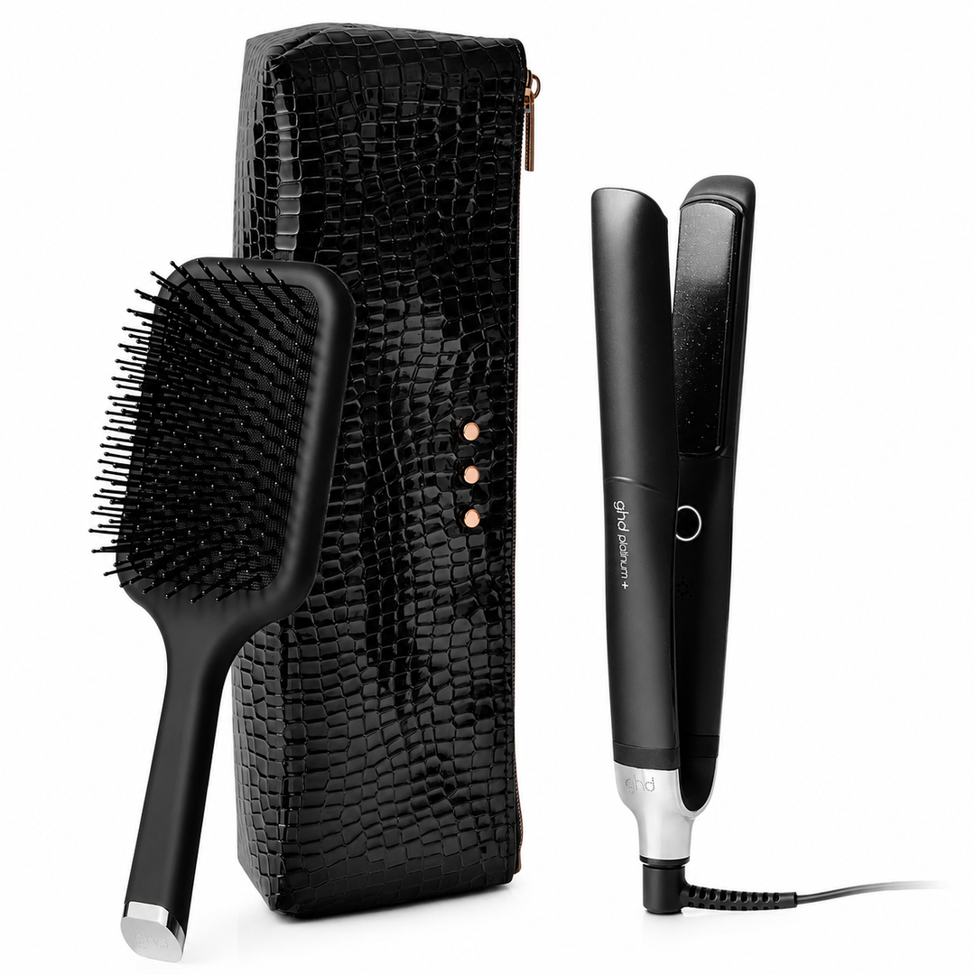 Trousse GHD Platinum+ comprenant un fer plat professionnel intelligent noir, une brosse plate GHD noire et un étui thermorésistant noir effet crocodile sur fond blanc.
