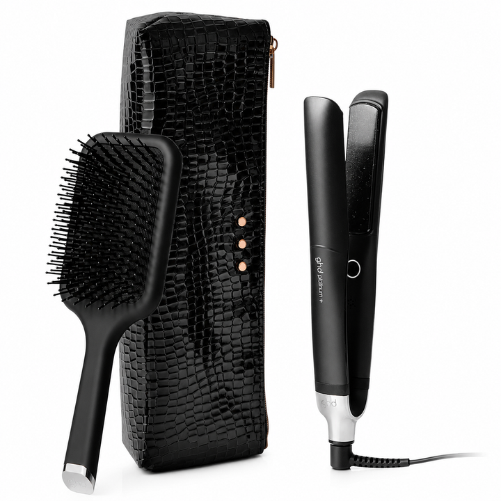 Trousse GHD Platinum+ comprenant un fer plat professionnel intelligent noir, une brosse plate GHD noire et un étui thermorésistant noir effet crocodile sur fond blanc.
