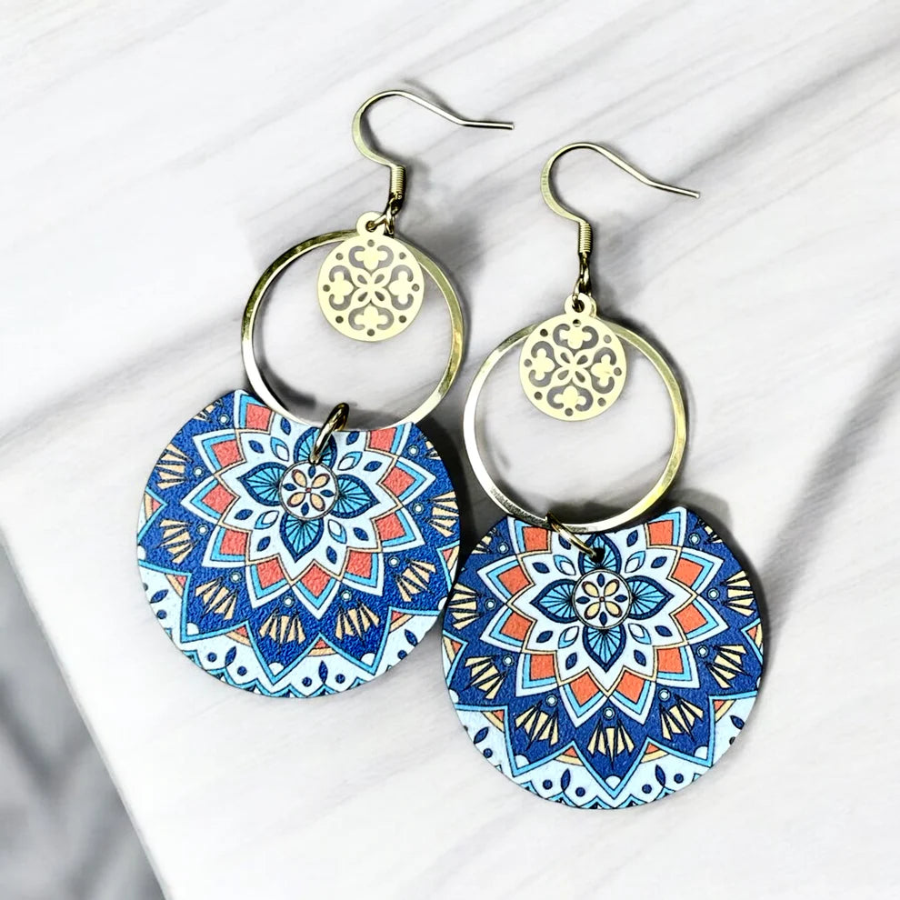 Boucles d’oreilles pendantes La Bohème Mandalas, en bois imprimé aux motifs mandala bleus et rouges, avec anneaux dorés et attaches hypoallergéniques.