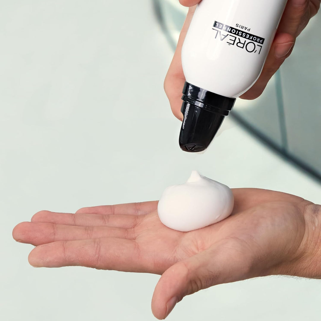 Mousse coiffante L’Oréal Professionnel Tecni.Art Volume Extra Full appliquée dans la main, texture légère et aérienne sortie d’un flacon blanc avec embout noir
