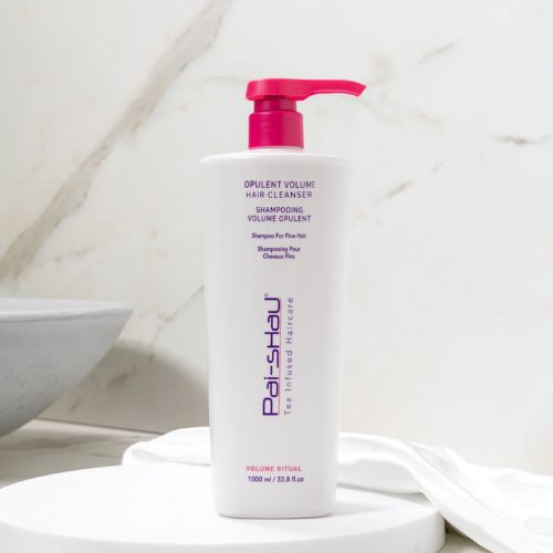 Flacon blanc mat de 1000 ml du Revitalisant Volume Opulent Pai-Shau avec pompe et bouchon rose. Soin capillaire végétalien volumisant pour cheveux fins ou colorés, grand format professionnel, posé sur fond blanc.