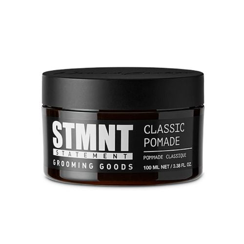 Pot noir STMNT Classic Pomade de 100 ml avec formule coiffante à base d’eau offrant contrôle fort et brillance naturelle sur fond blanc.