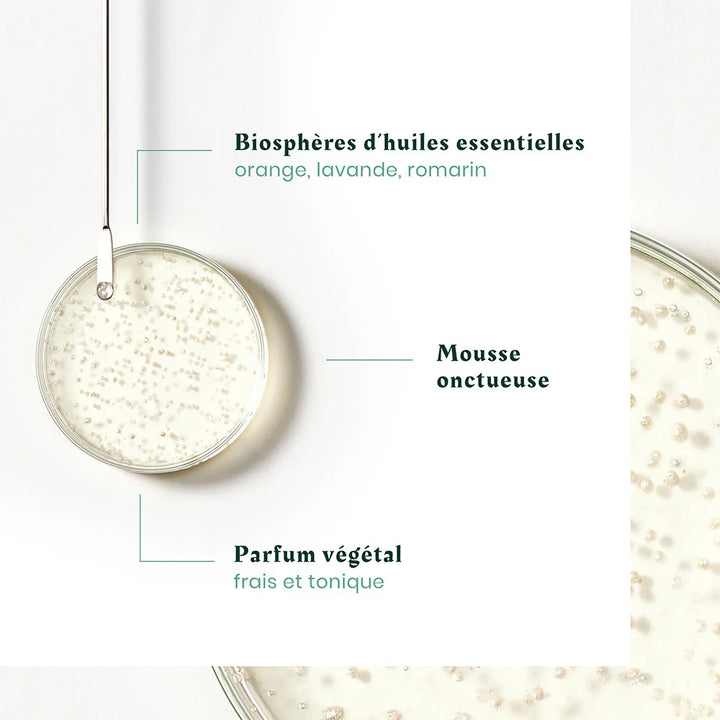 Zoom sur texture du shampoing Triphasic avec micro-billes et mention biosphères d’huiles essentielles orange lavande romarin, fond clair esthétique