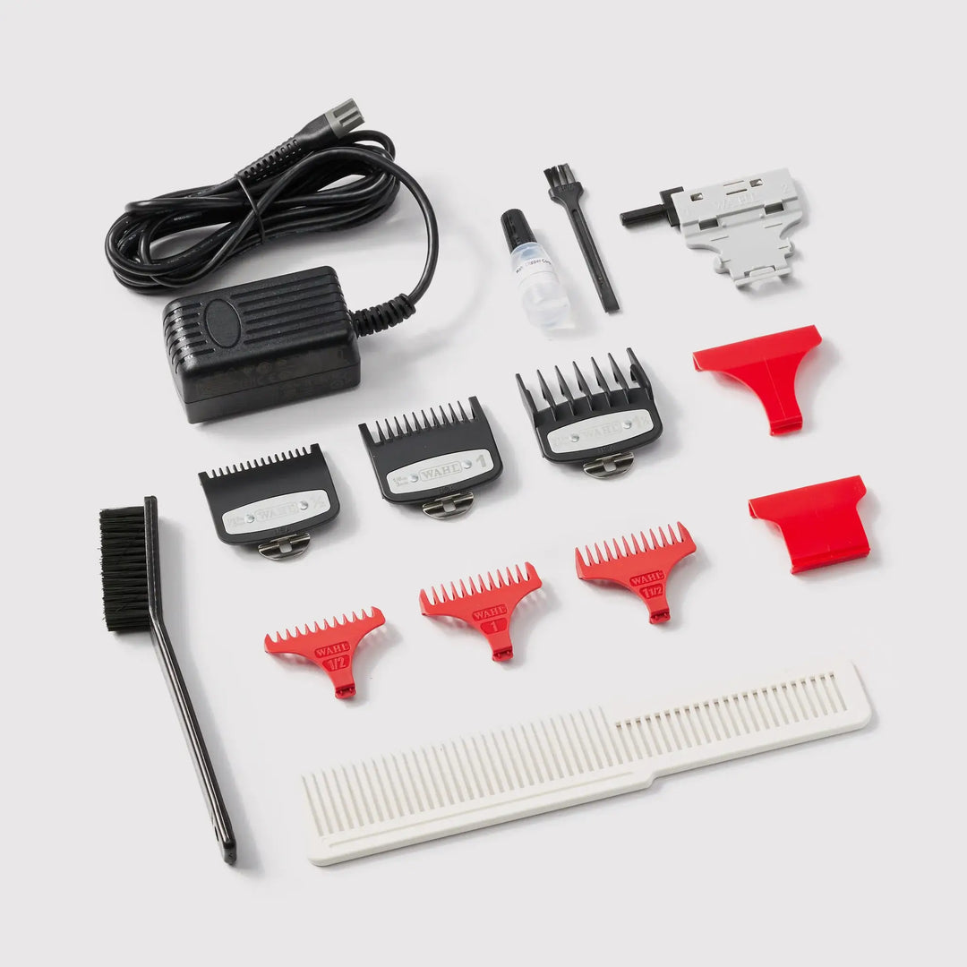 Kit d’accessoires WAHL pour tondeuse professionnelle incluant sabots de coupe, peigne, huile, brosse de nettoyage et chargeur, présenté sur fond blanc.