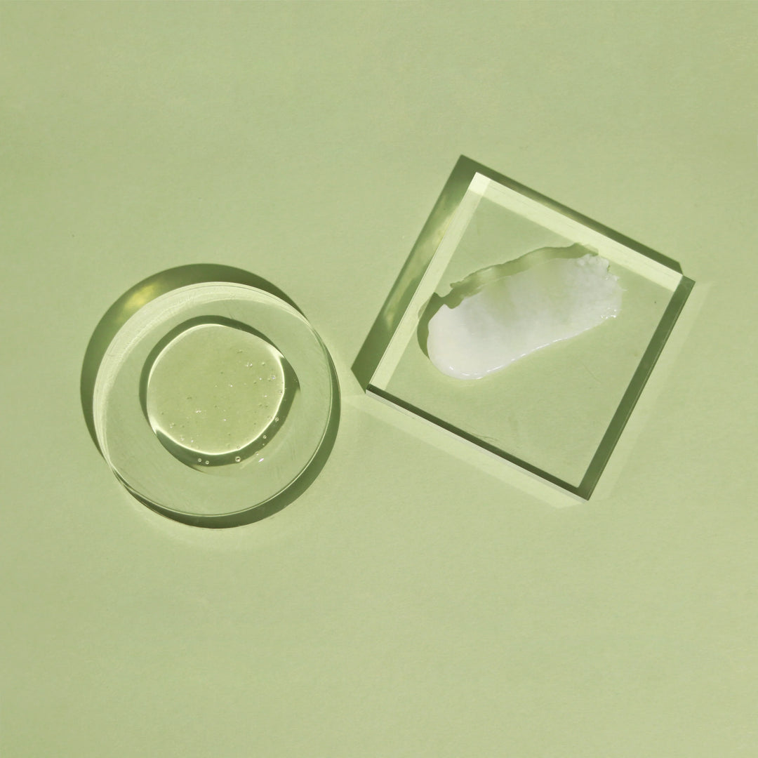 Textures de soins capillaires ACT/IV présentées sur fond vert, avec gel translucide et crème blanche sur supports en verre, illustrant des formules légères et hydratantes pour cheveux et cuir chevelu.