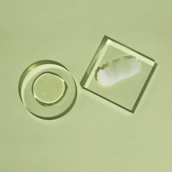 Textures de soins capillaires ACT/IV présentées sur fond vert, avec gel translucide et crème blanche sur supports en verre, illustrant des formules légères et hydratantes pour cheveux et cuir chevelu.