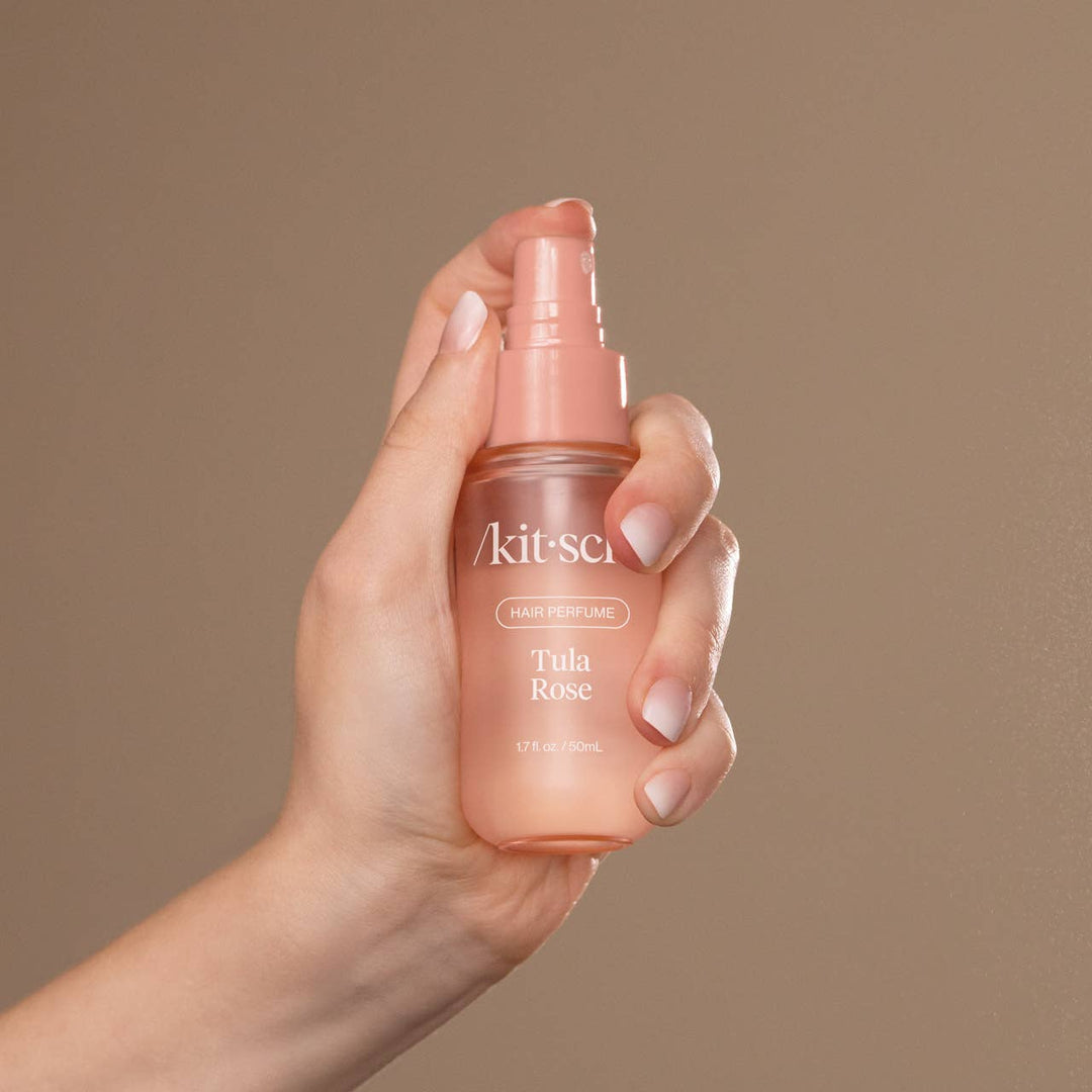 Gros plan d'une main utilisant le parfum pour cheveux KITSCH Tula Rose 50 ml. Vaporisateur diffusant une fine brume parfumée pour des cheveux frais et délicatement parfumés.