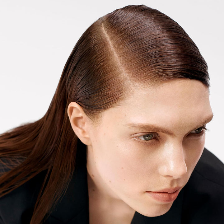 Cheveux lisses et brillants avec raie sur le côté après utilisation d’un spray coiffant fixation flexible, rendu naturel et discipliné sur fond clair studio.