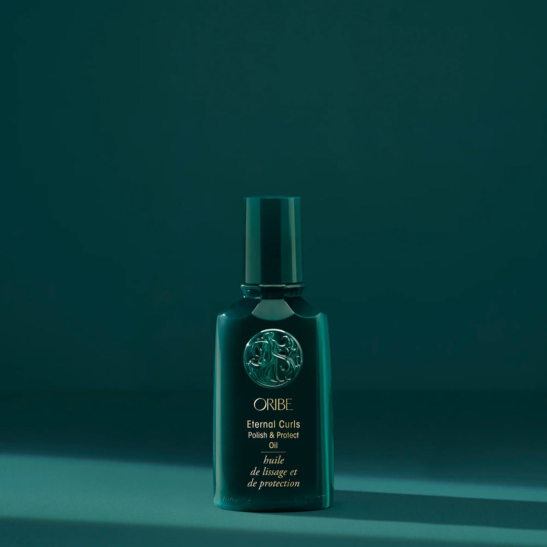 Huile capillaire Oribe Eternal Curls Polish & Protect Oil présentée sur fond vert foncé pour nourrir, protéger et faire briller les cheveux bouclés.