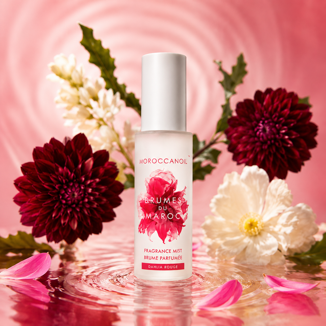Brume parfumée Moroccanoil Dahlia Rouge 100 ml avec bouteille givrée rose, fleurs bordeaux et pétales roses sur fond aquatique rosé raffiné.