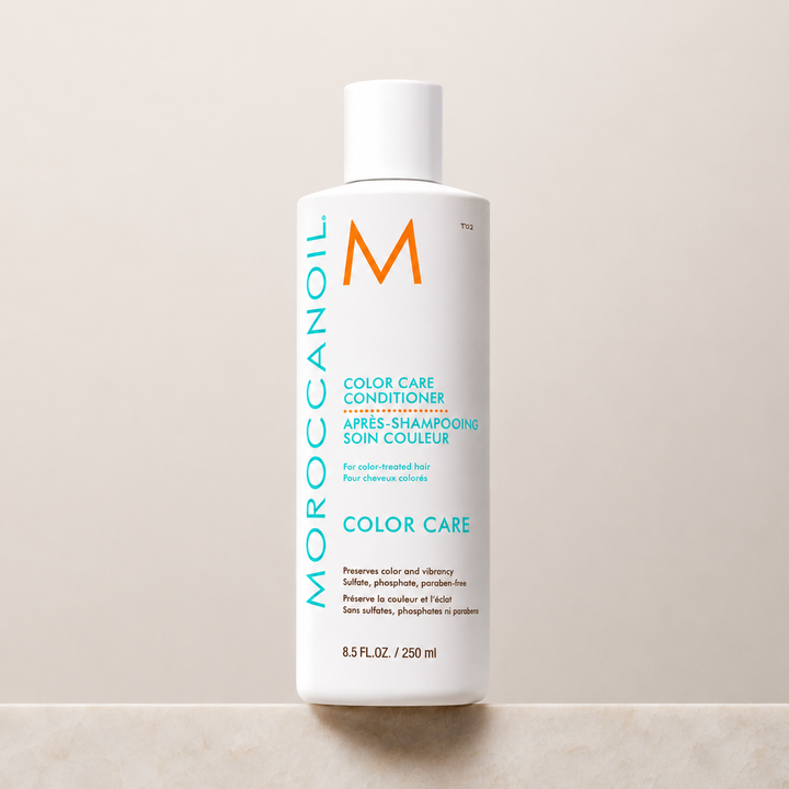 Après-shampoing Moroccanoil Soin Couleur 250 ml pour cheveux colorés, bouteille blanche avec bouchon, logo turquoise et orange, photographiée sur un fond beige minimaliste.