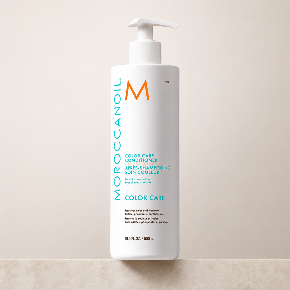 Après-shampoing Moroccanoil Soin Couleur 500 ml pour cheveux colorés, bouteille blanche avec pompe, logo turquoise et orange, photo produit sur fond beige épuré.