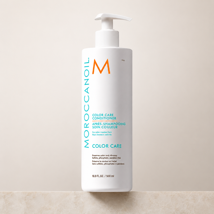 Après-shampoing Moroccanoil Soin Couleur 500 ml pour cheveux colorés, bouteille blanche avec pompe, logo turquoise et orange, photo produit sur fond beige épuré.