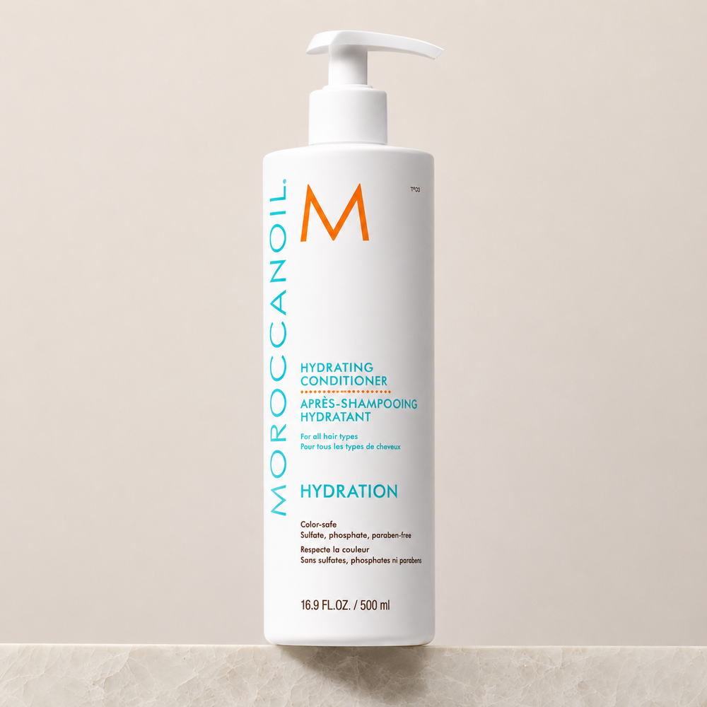 Après-shampoing hydratant Moroccanoil Hydration 500 ml avec pompe blanche, bouteille blanche et étiquette turquoise, photographié sur fond beige pour boutique en ligne.