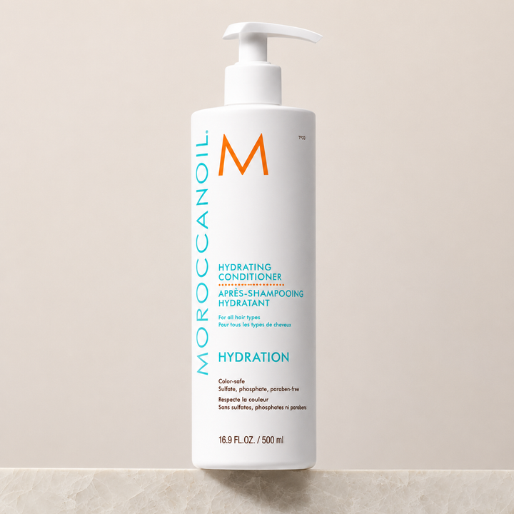 Après-shampoing hydratant Moroccanoil Hydration 500 ml avec pompe blanche, bouteille blanche et étiquette turquoise, photographié sur fond beige pour boutique en ligne.
