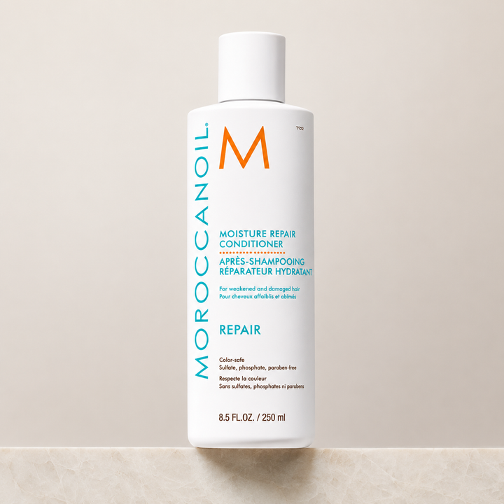 Après-shampoing réparateur hydratant Moroccanoil 250 ml en bouteille blanche avec bouchon blanc, étiquette turquoise et orange, présenté sur fond beige en studio.