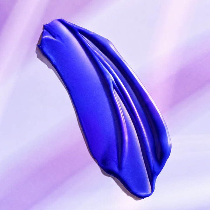 Texture violette de l'Après-shampooing Violet Blond Parfait Moroccanoil appliquée en bande sur un fond aux reflets lavande, illustrant les pigments violets qui neutralisent les reflets jaunes des cheveux blonds.