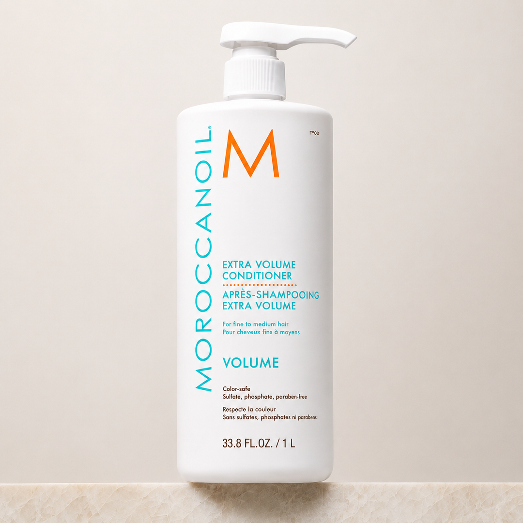 Après-shampoing Extra Volume Moroccanoil 1 litre avec pompe blanche, bouteille grand format blanche, étiquette turquoise et orange, soin volumisant pour cheveux fins sur fond beige épuré.