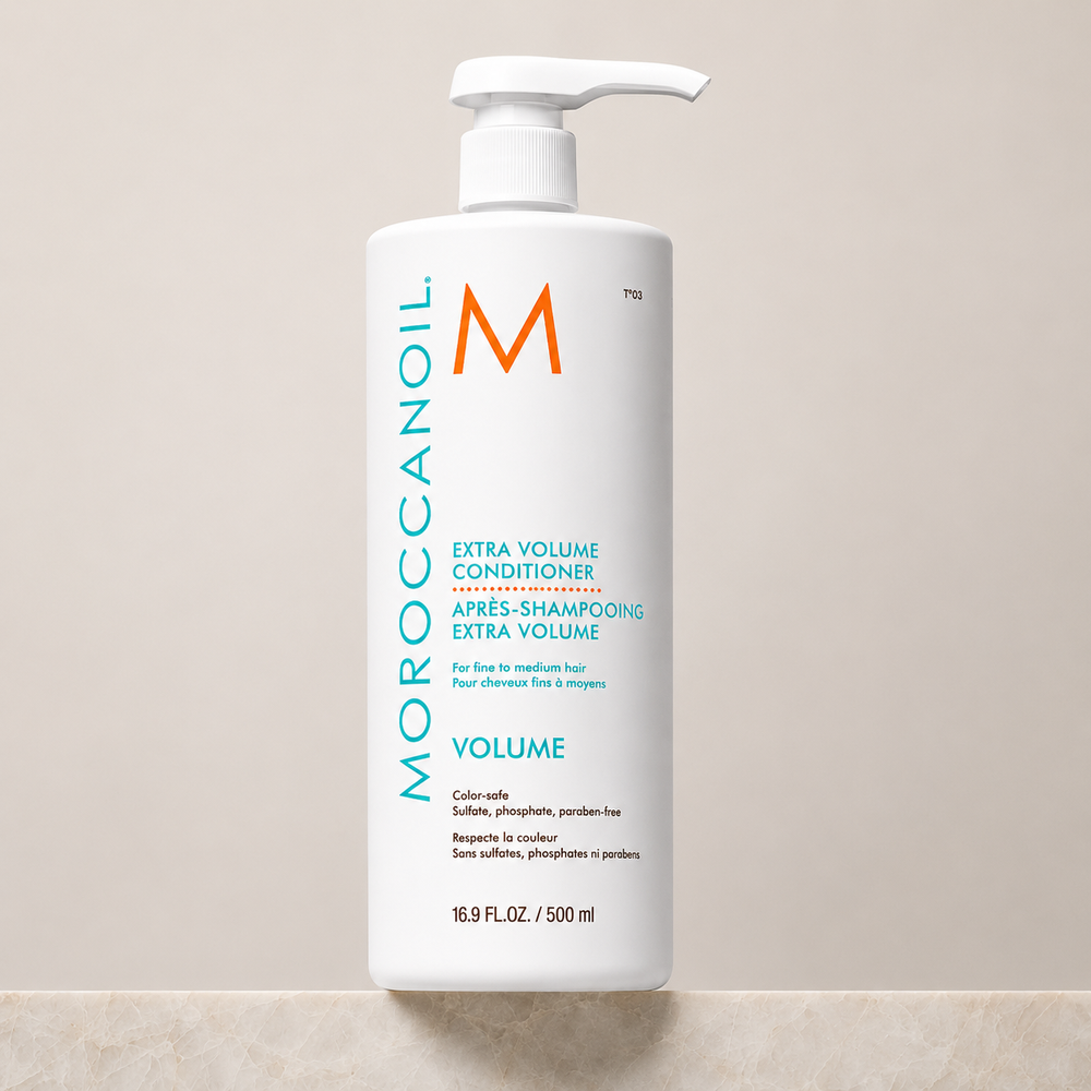 Après-shampoing Extra Volume Moroccanoil 500 ml avec pompe blanche, bouteille blanche et étiquette turquoise, revitalisant volumisant pour cheveux fins, photo produit sur fond beige professionnel.