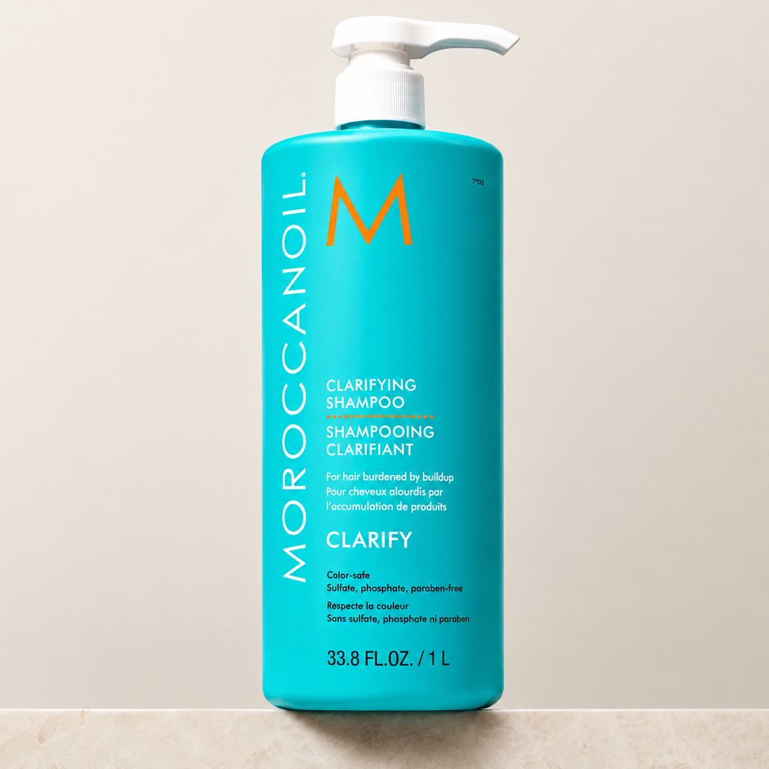 Shampoing clarifiant Moroccanoil 1 L avec pompe blanche, bouteille turquoise au fini mat sur fond beige. Format professionnel pour nettoyer en profondeur les cheveux, éliminer l'accumulation de produits et purifier le cuir chevelu.