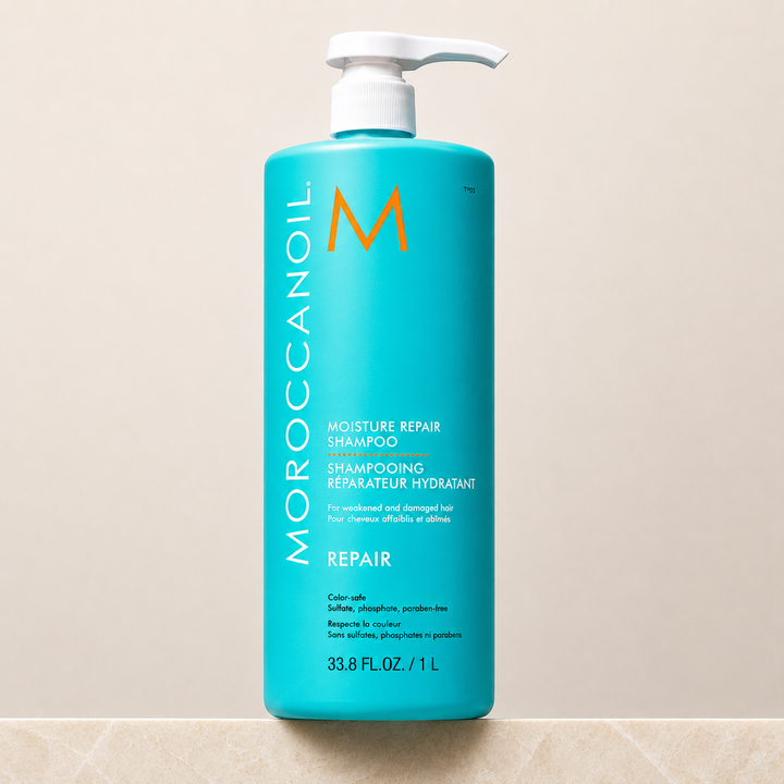 Bouteille turquoise Moroccanoil Shampoing Réparateur Hydratant avec bouchon blanc, format 1 Litre , présentée sur fond beige clair. Soin capillaire réparateur à l’huile d’argan pour cheveux abîmés.