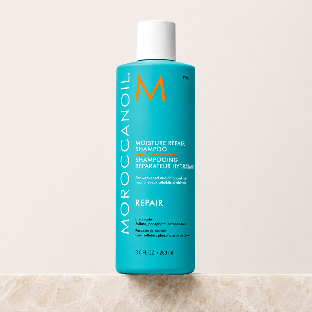 Bouteille turquoise Moroccanoil Shampoing Réparateur Hydratant avec bouchon blanc, format 250 ml , présentée sur fond beige clair. Soin capillaire réparateur à l’huile d’argan pour cheveux abîmés.