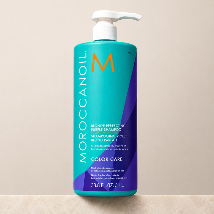 Shampoing Violet Blond Parfait Moroccanoil 1 litre en bouteille turquoise et violet avec pompe blanche sur fond beige épuré, image professionnelle de shampoing violet neutralisant pour cheveux blonds et gris.