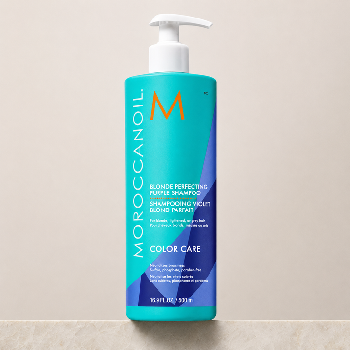 Shampoing Violet Blond Parfait Moroccanoil 500 ml en bouteille turquoise et violet avec pompe blanche, posé sur un comptoir beige, photo studio haute résolution pour cheveux blonds, gris ou méchés.