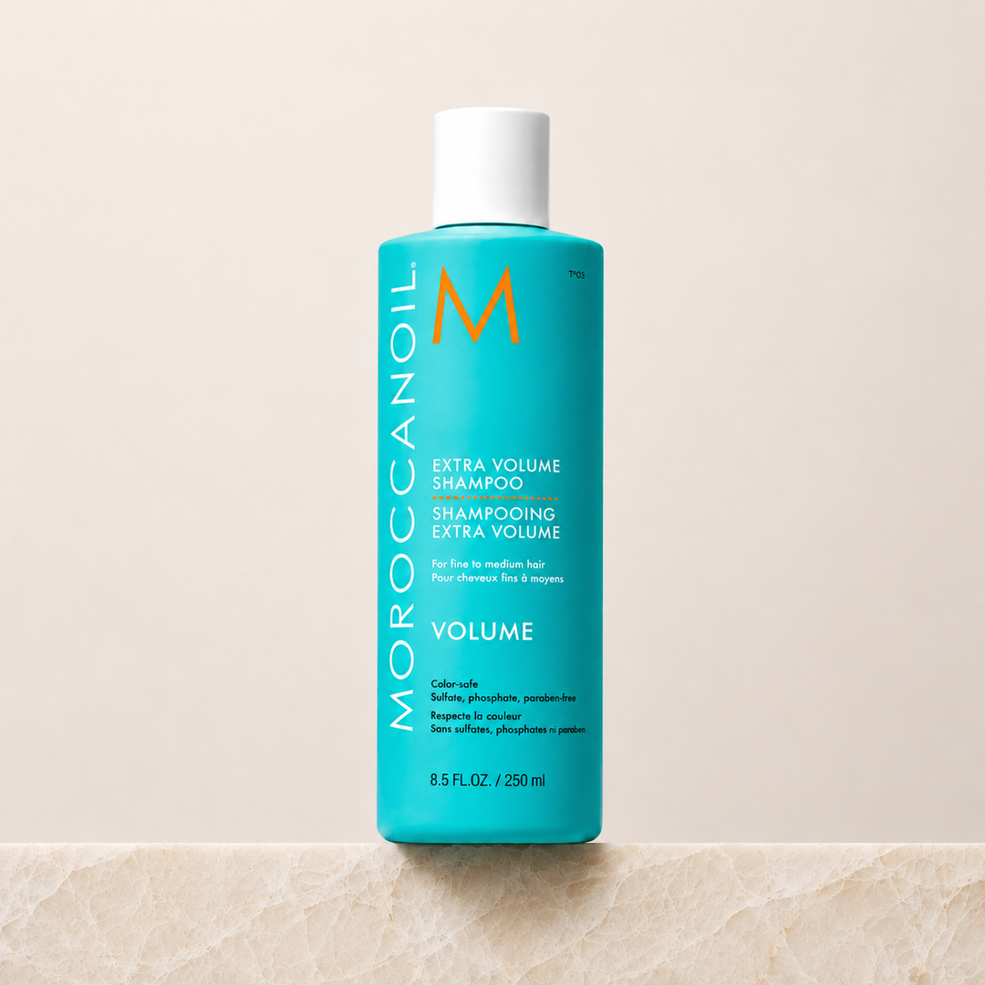 Shampoing Extra Volume Moroccanoil 250 ml  en bouteille turquoise avec bouchon blanc ou pompe blanche, étiquette blanche et orange, photo professionnelle sur fond beige, soin volumisant pour cheveux fins