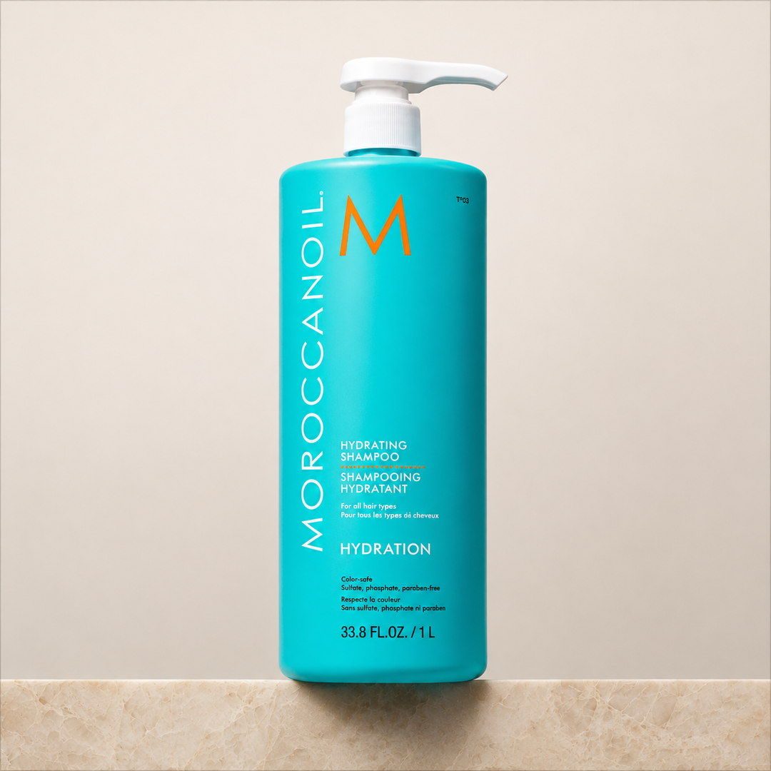 Shampoing hydratant Moroccanoil 1 L en bouteille turquoise avec pompe blanche, fond beige épuré, soin hydratant pour cheveux.